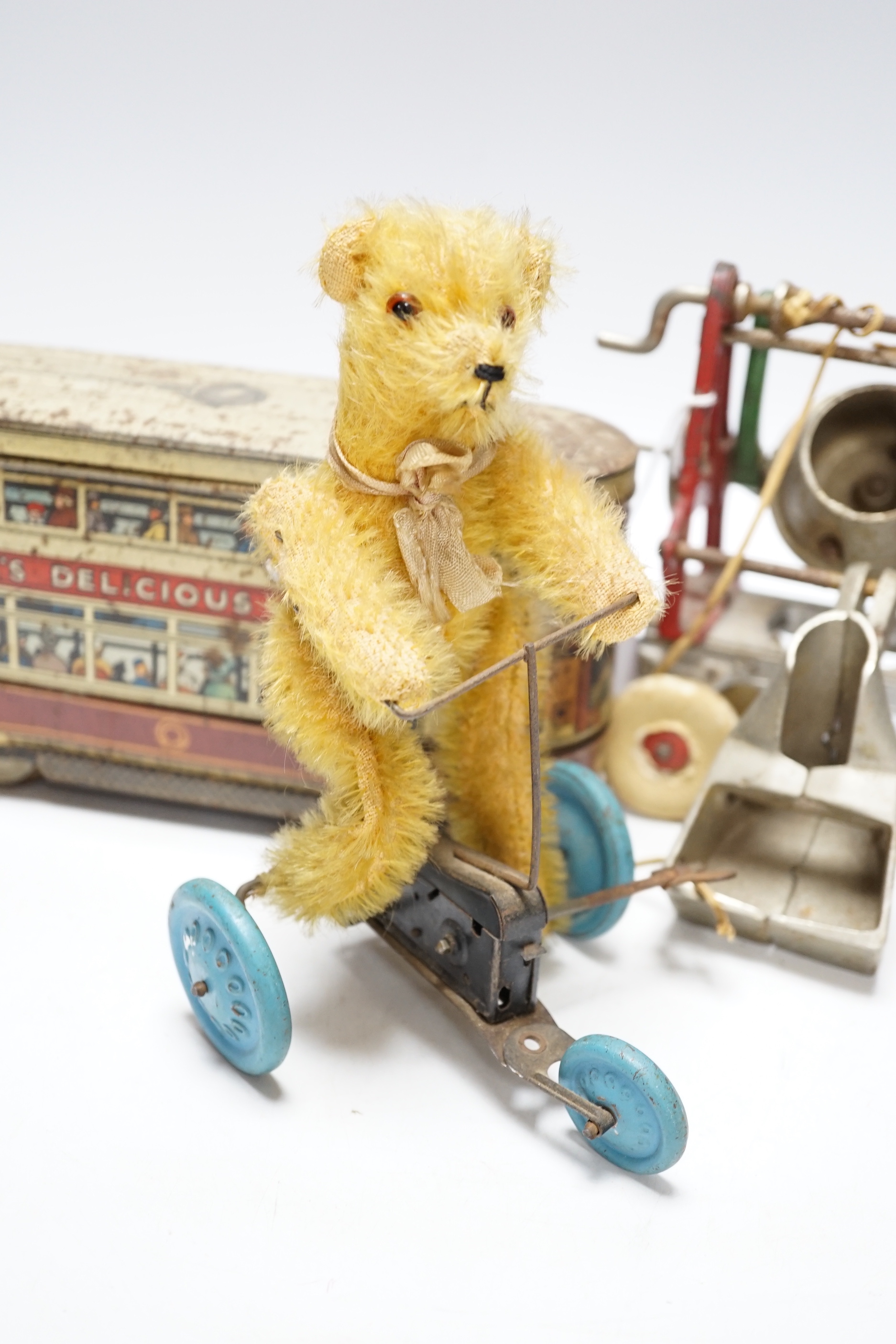 Three tinplate/cast iron toys; a Jaeger cast iron concrete mixer, a Carr’s tinplate biscuit tin in the form of a tram, and a clockwork teddy bear on a tricycle, tram 22cm long